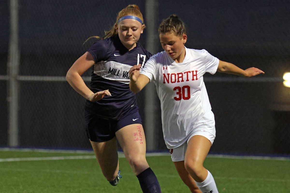 Racing her opponent, junior Emma Carbajo dribbles the ball up the field. 