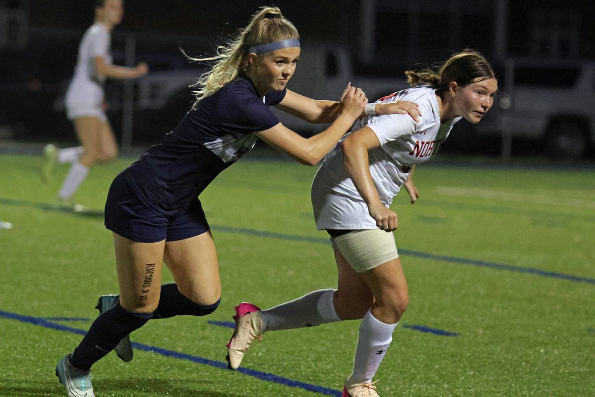 Shoving past her opponent, senior Addison Long chases after the ball.