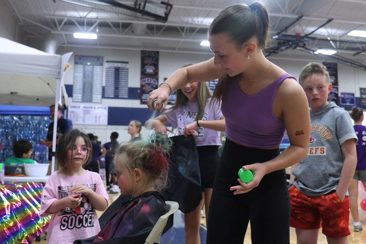 Junior Lilli Verbenec puts pink hair spray in a kid’s hair. 