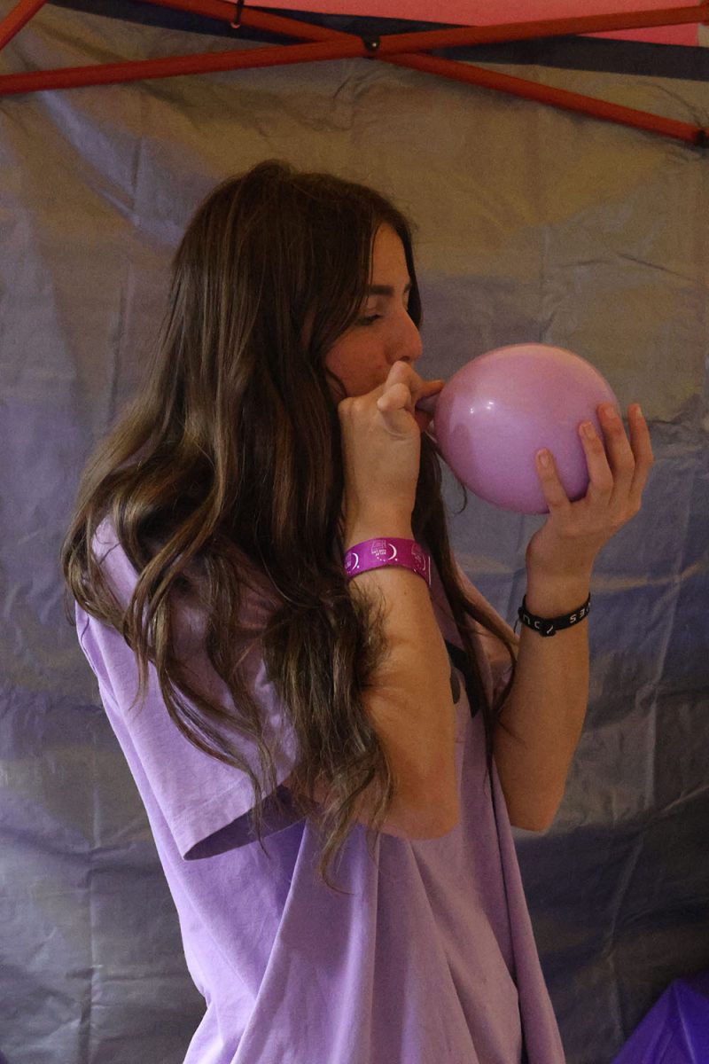 Decorating her booth, junior Kinley Ruder blows up a balloon. 
