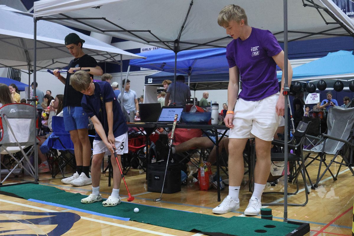 Running his booth, freshman Calton Bierl watches a kid play golf. 
