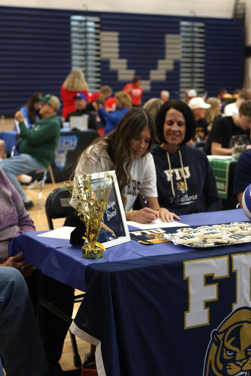 Pen in hand, senior Ashlyn Blazer signs her paper and commits to Florida International University.