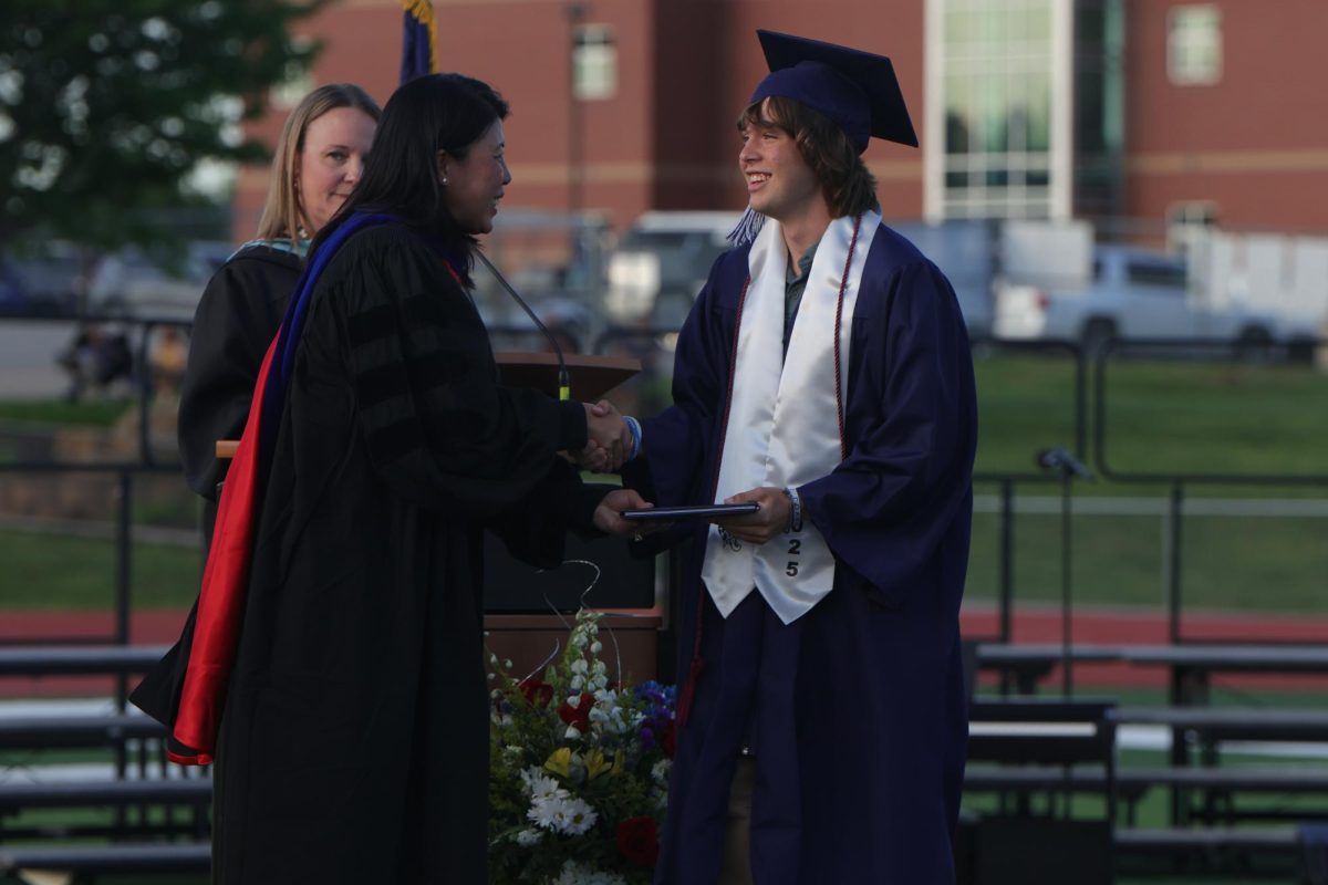 Walking across the stage, senior Thomas Helm receives his diploma.
