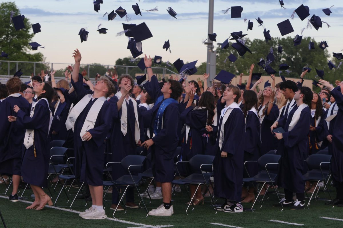 Looking up, the senior class throws their caps in the air.
