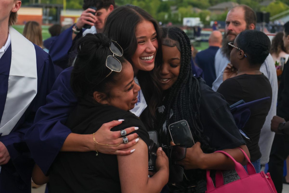 Hugging her family, senior Emersyn Jones smiles after she walks off the field.
