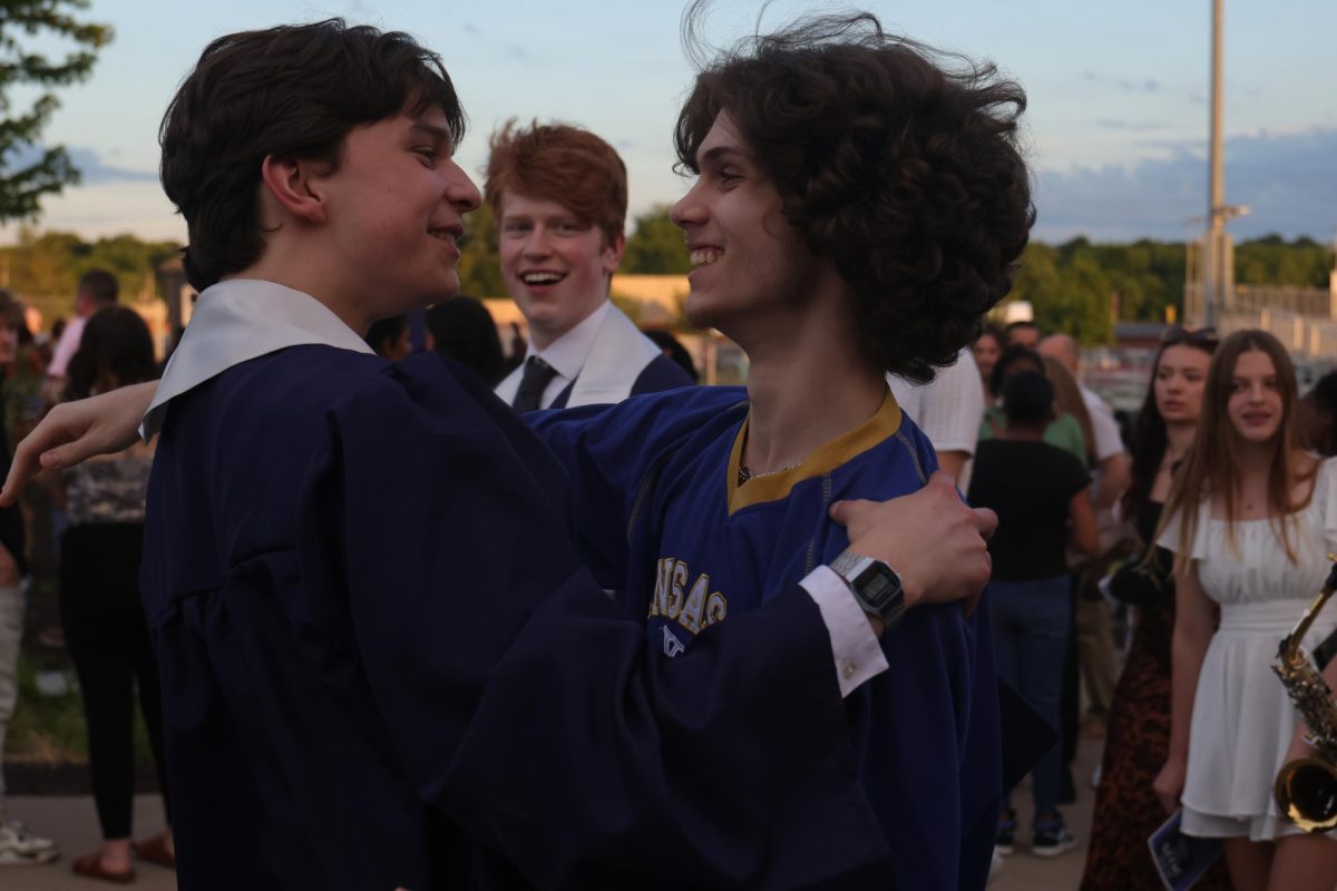 Hugging, senior Kai McGarry greets someone after the graduation ceremony. 
