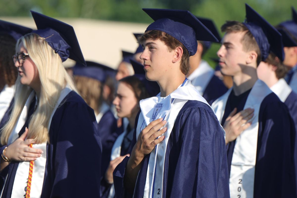Hand on his heart, senior Jacob Muntzel looks at the flag during the national anthem. 
