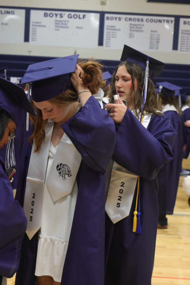 Helping her friend, senior Lily Folendore fixes senior Aubrie Barton’s stoll.

