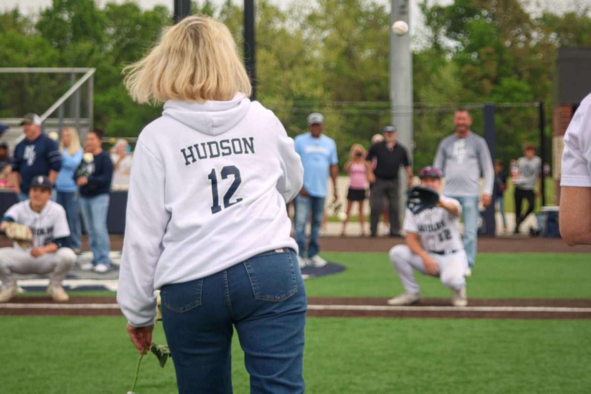Throwing the ball, Mother of senior Hudson Powers throws out the first pitch to her son.
