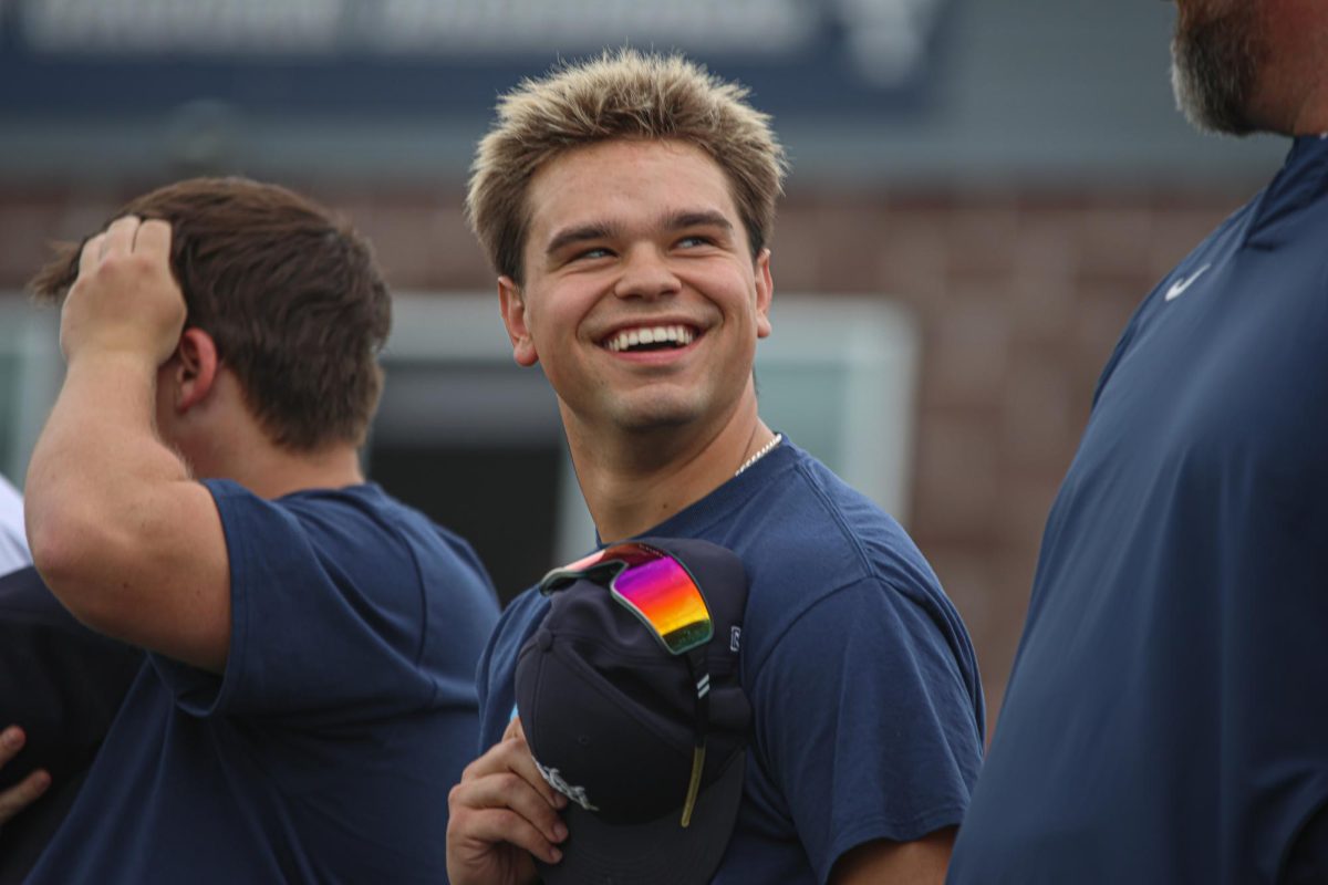 Smiling, senior Zach Zaldivar laughs with his coach during the national anthem.
