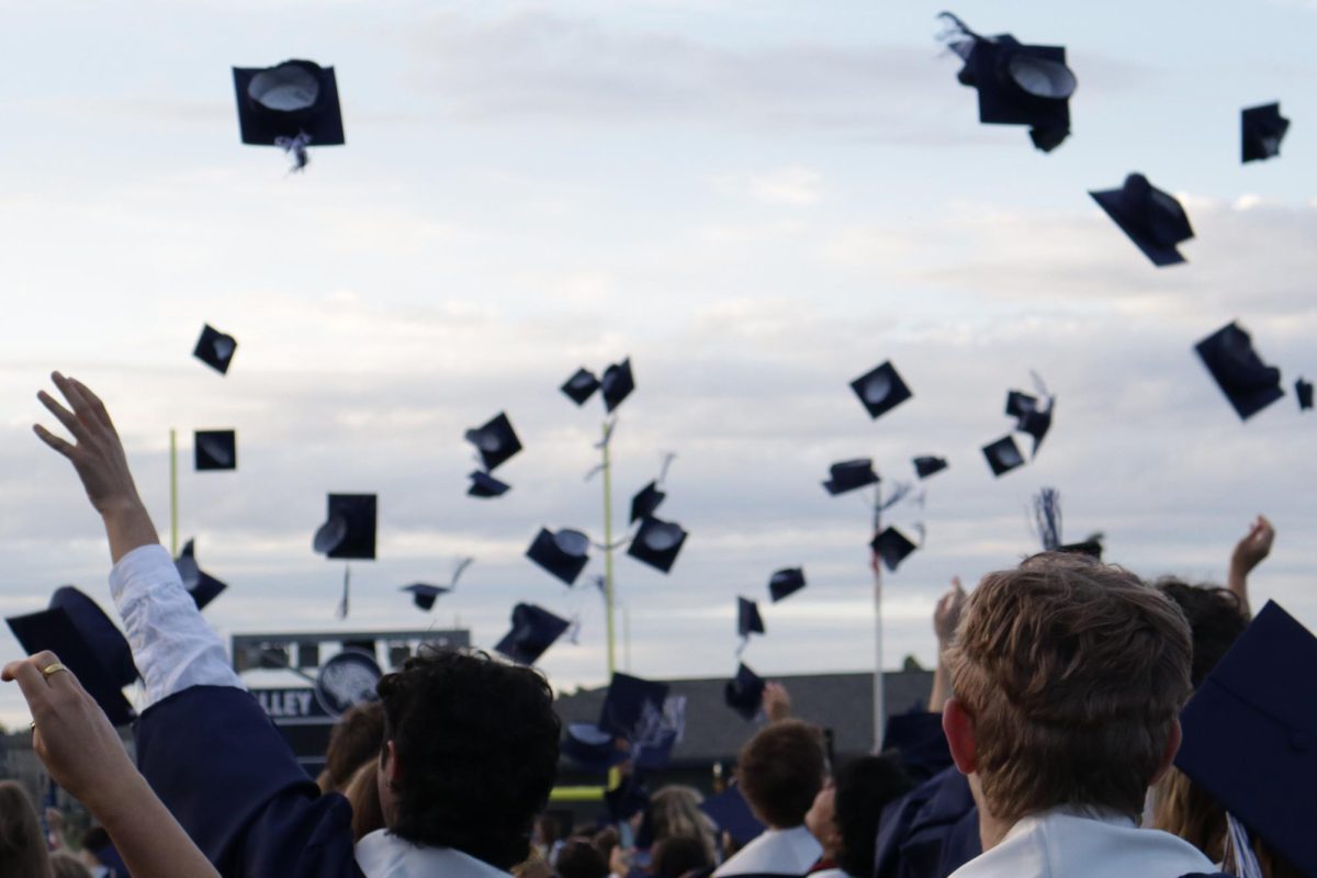 The senior class of 2025 excitedly throws their caps in the air in celebration of graduating.