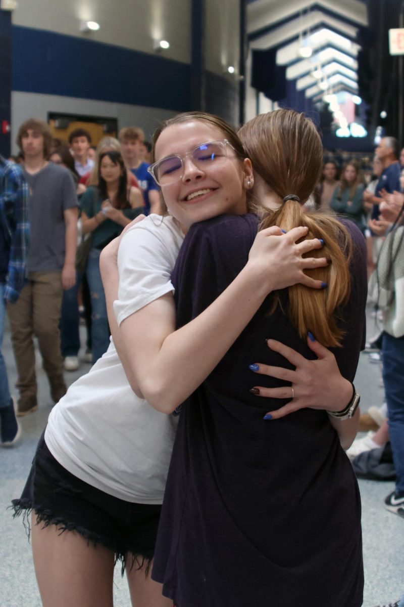 With her eyes closed, senior Bella Supica hugs her friend during the senior walk-through.