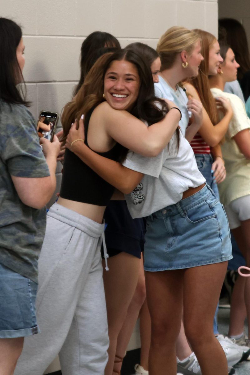 With a smile on her face, senior Emersyn Jones leans in to hug her friend.