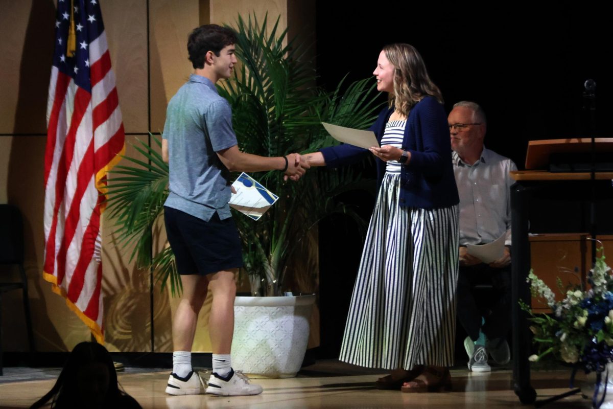 After receiving the J. Trenton Hughes Scholarship, senior Noah Pham shakes hands with counselor Erin Hayes.