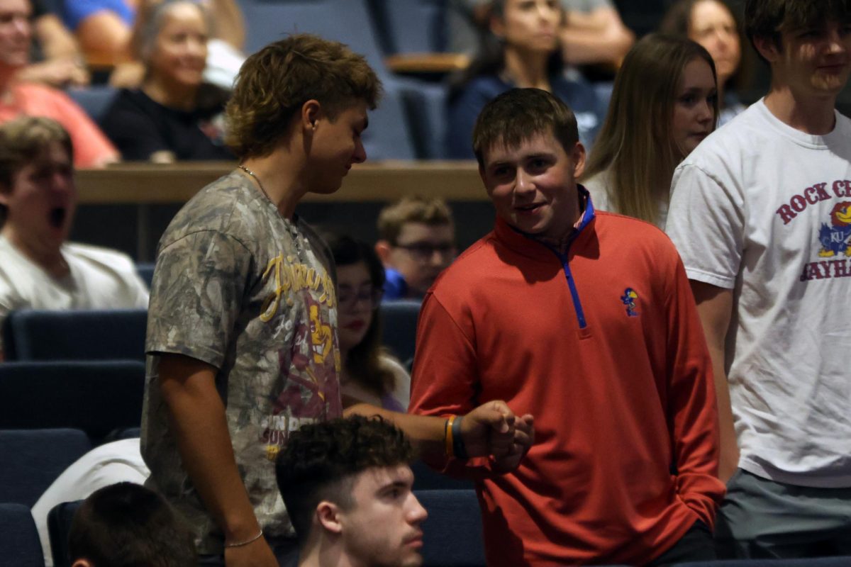 Standing up to be recognized, senior Carter Coup gives his friend a fist bump. 
