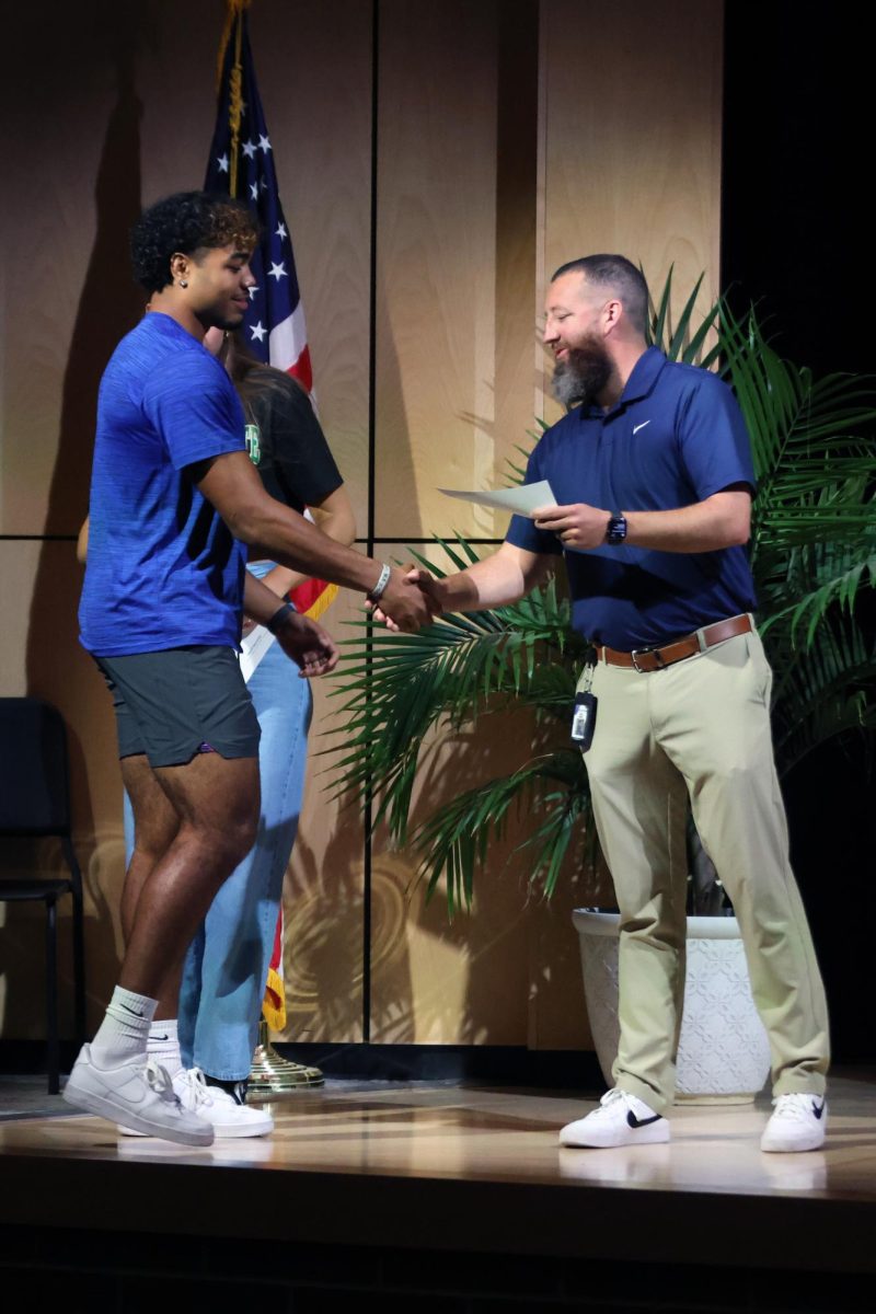 Shaking hands with the Athletic Director Brent Bechard, senior Jayden Woods receives the Distinguished Athletic award.