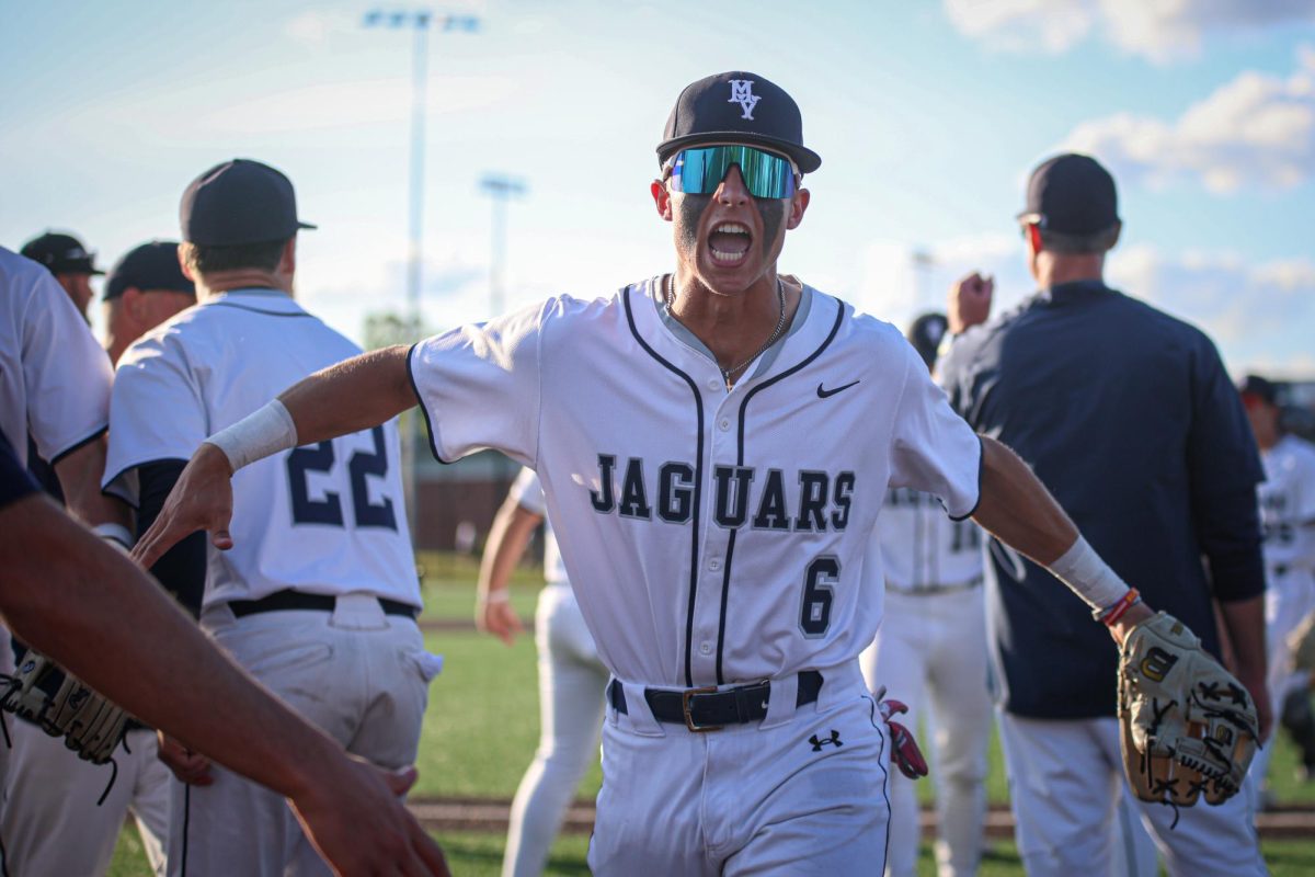 Yelling in excitement, junior Blake Jay gives his teammates a high five.