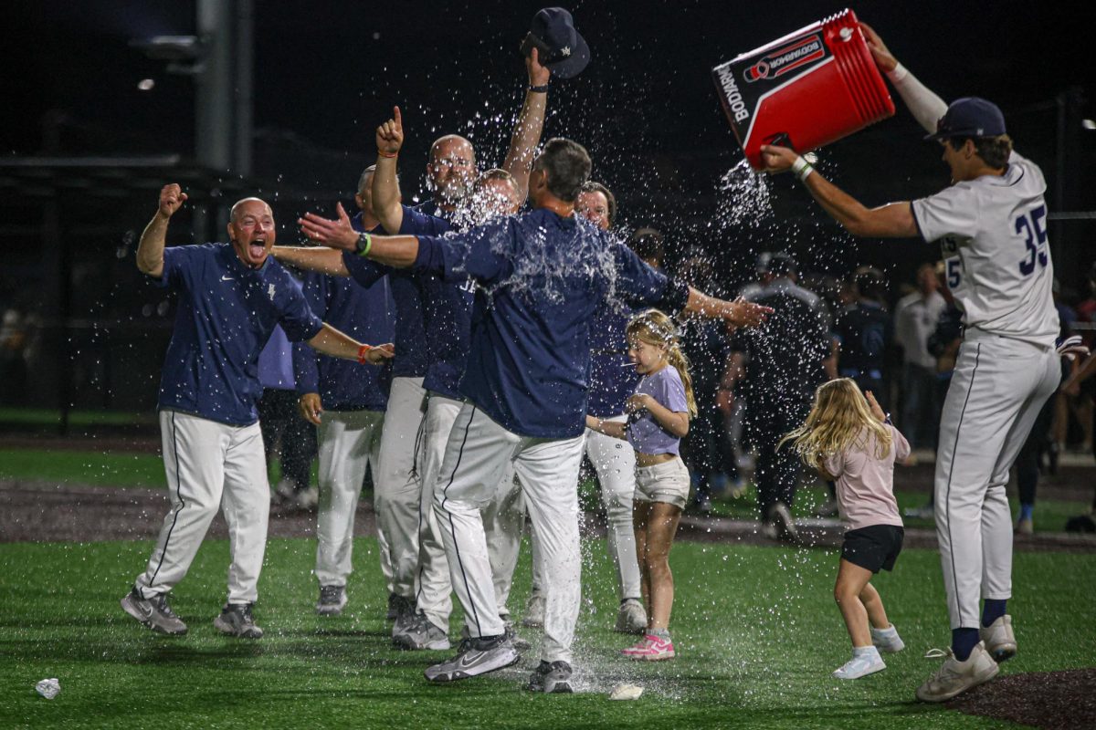 With his hands out, Head Coach Jeff Strickland celebrates with his fellow coaches.