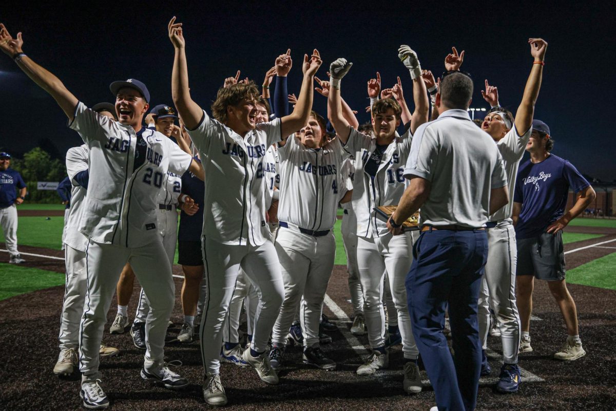 With their hands in the air, the baseball team prepares to receive the trophy.  