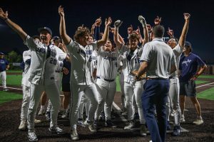 With their hands in the air, the baseball team prepares to receive the trophy.  
