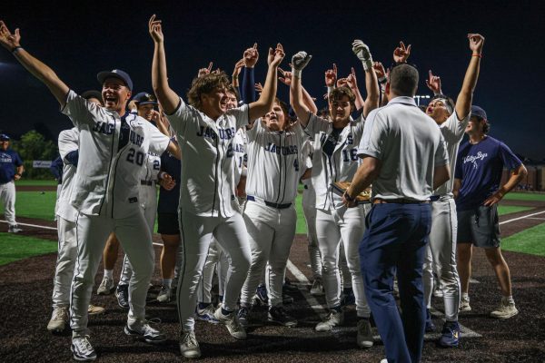 With their hands in the air, the baseball team prepares to receive the trophy.  