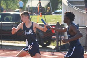 Freshman Gabe Muttai passes the baton to junior Gus Malone in the boys 4x800 relay on May 15. 