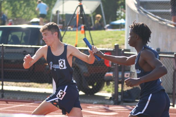 Freshman Gabe Muttai passes the baton to junior Gus Malone in the boys 4x800 relay on May 15. 