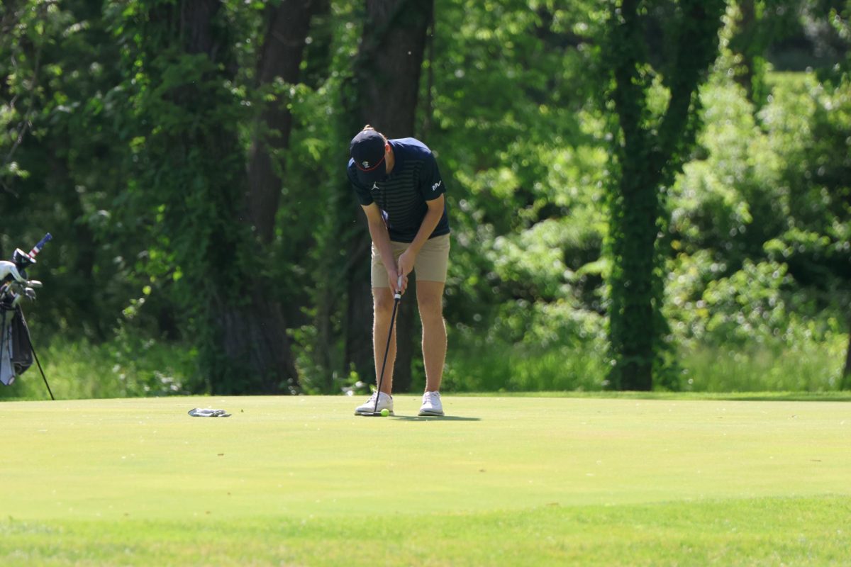 Looking down, sophomore Eli Platz hits the ball.