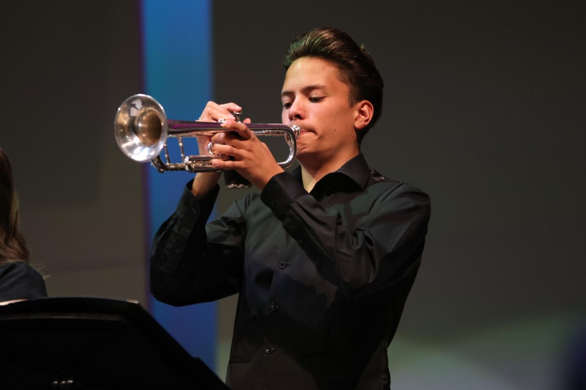 Looking down, sophomore Turner Bruce plays his trumpet. 