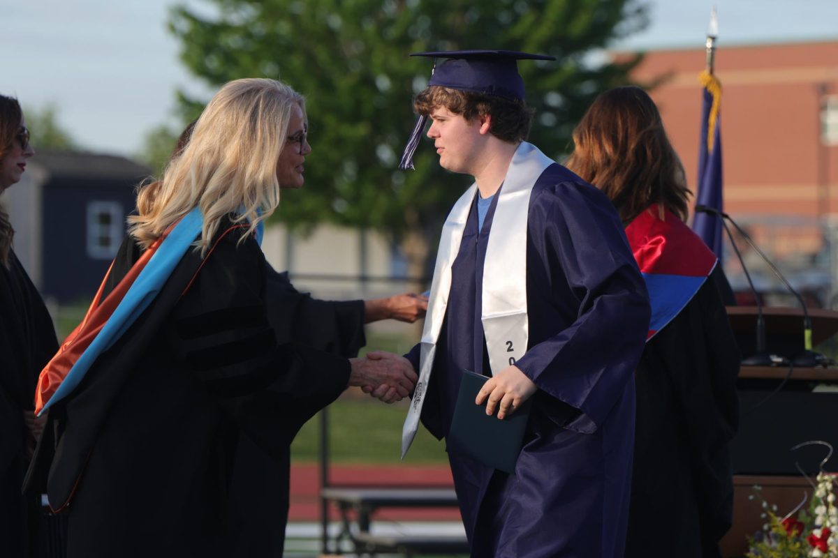 Shaking hands, senior Reid Ellis walks past Principal Dr. Gail Holder.
