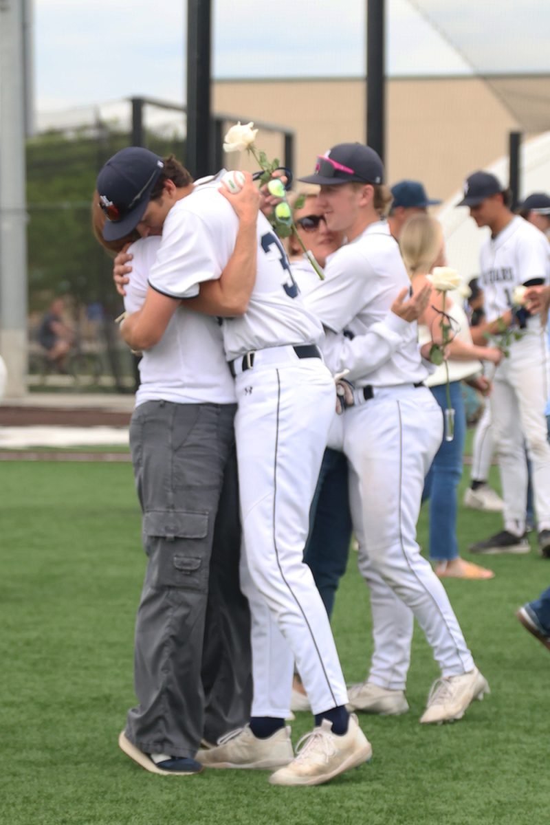 After the annual senior night opening game pitch, senior Isaac Sauder hugs his mom.