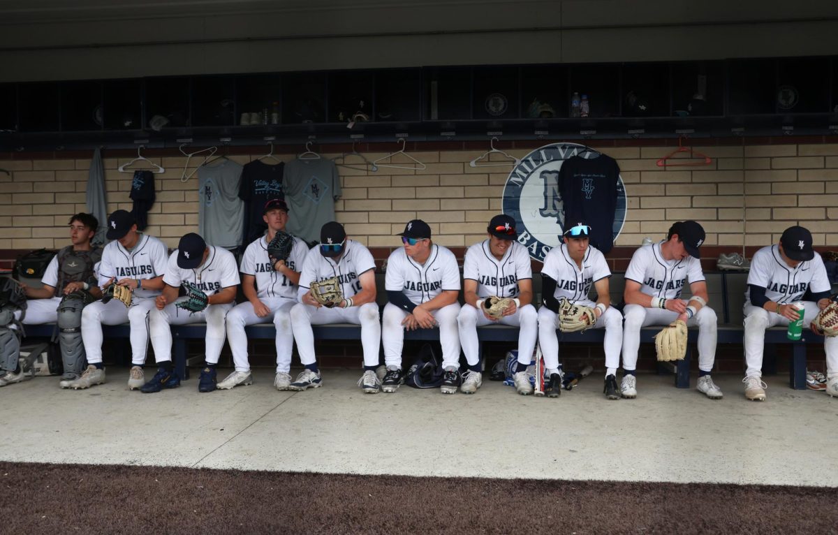 Sitting as a team, the players await in the dugout for their names to be called to take the field.
