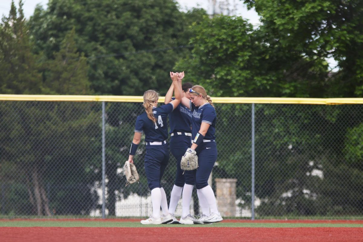 Pinkies together, sophomores Faith Pittenger, Addison Moeller, and Peyton Heinrich bump hips in the outfield in the first round of the regional tournament Thursday, May 22..