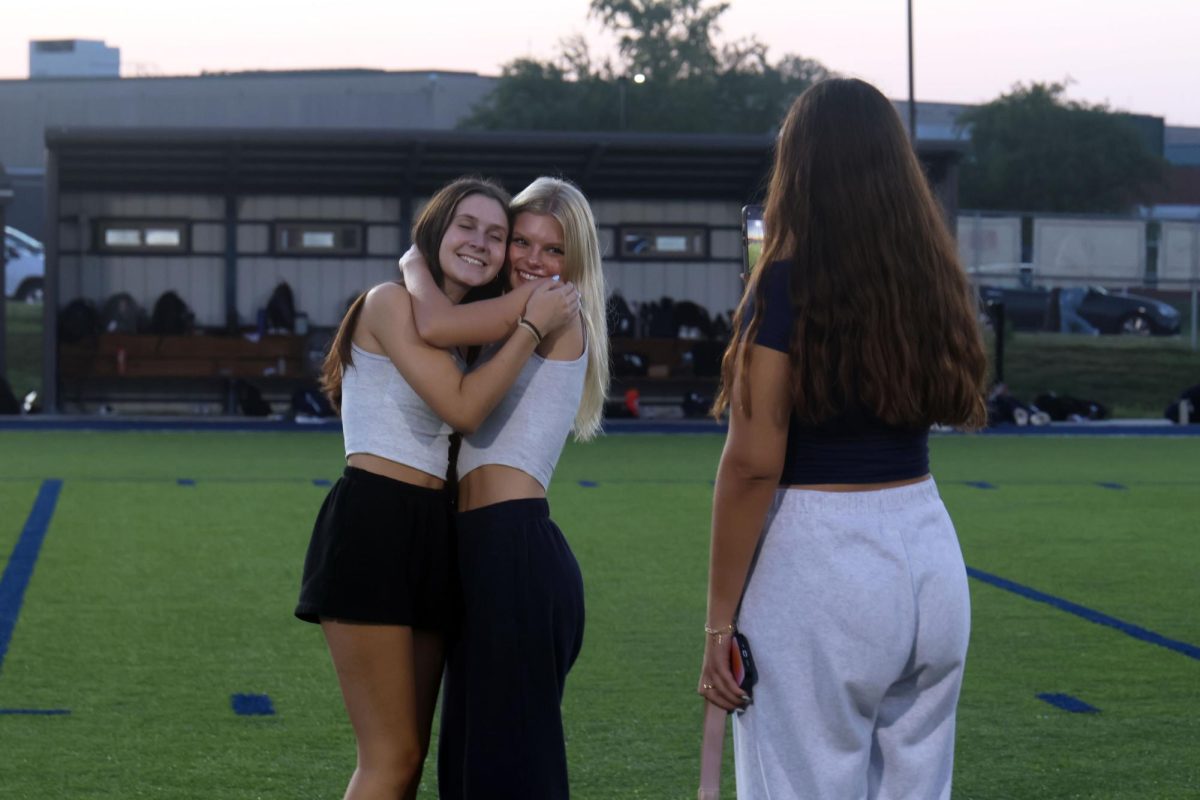 Hugging, seniors Lilly Feuerborn and Eden Christian smile for a photo.
