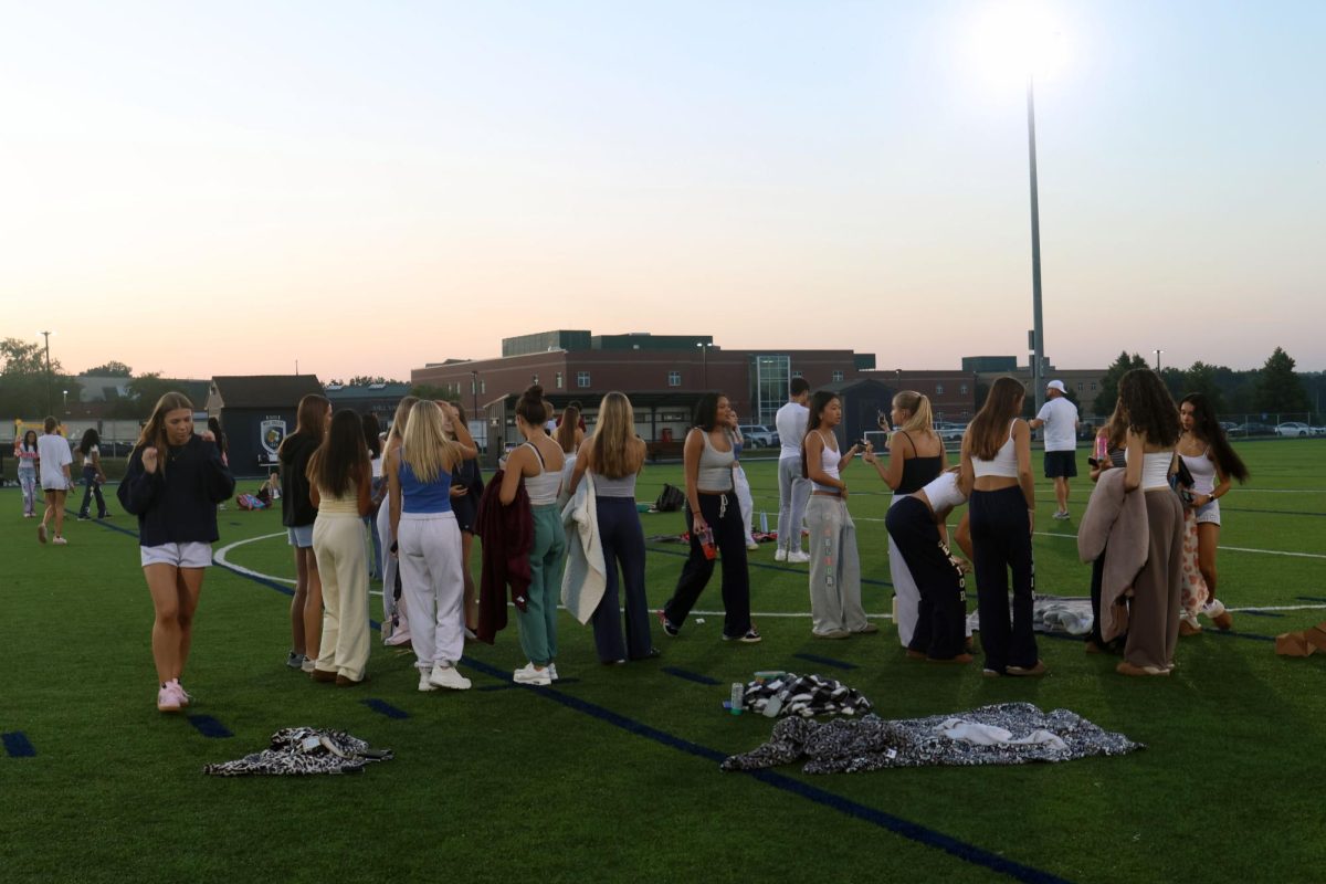 Seniors hold their blankets and talk in their friend groups as the sun rises.
