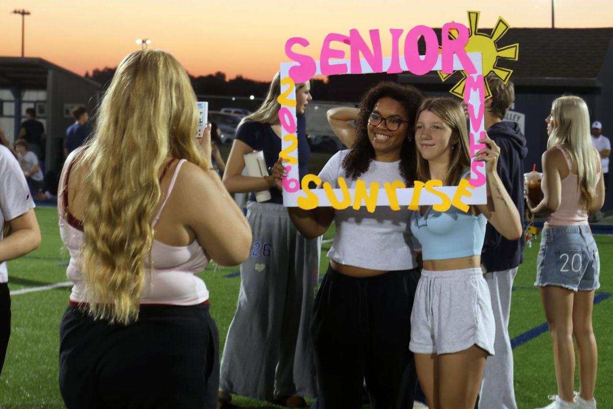 Seniors Riley Thomas and Daneka Jones pose with a handmade senior sunrise frame as senior Emma Brooks takes their photo, Wednesday Aug. 20.