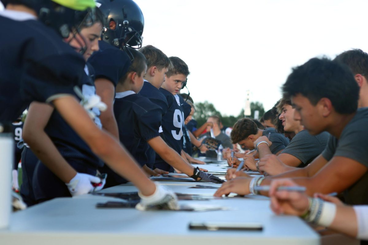 High school football team members give autographs to junior jag football players.