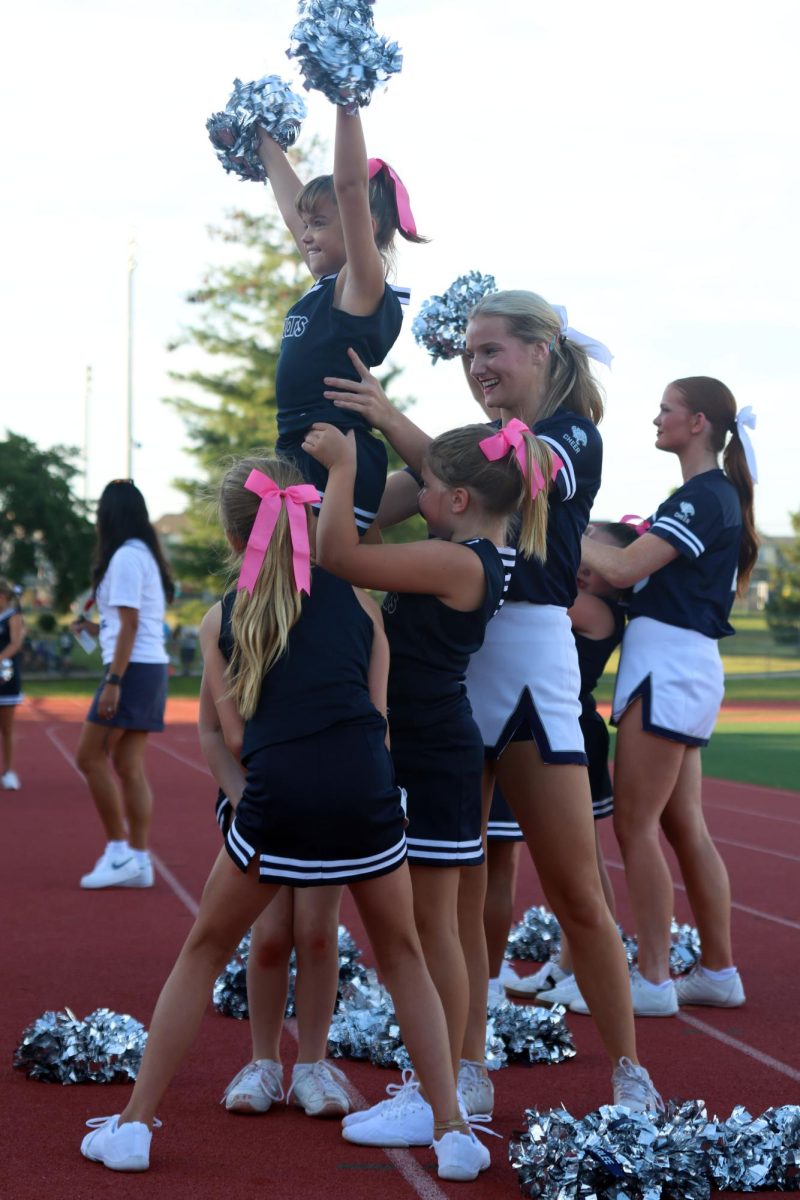 Smiling, senior Brynlee Sword helps spot junior jag flyer as she is lifted into the air.
