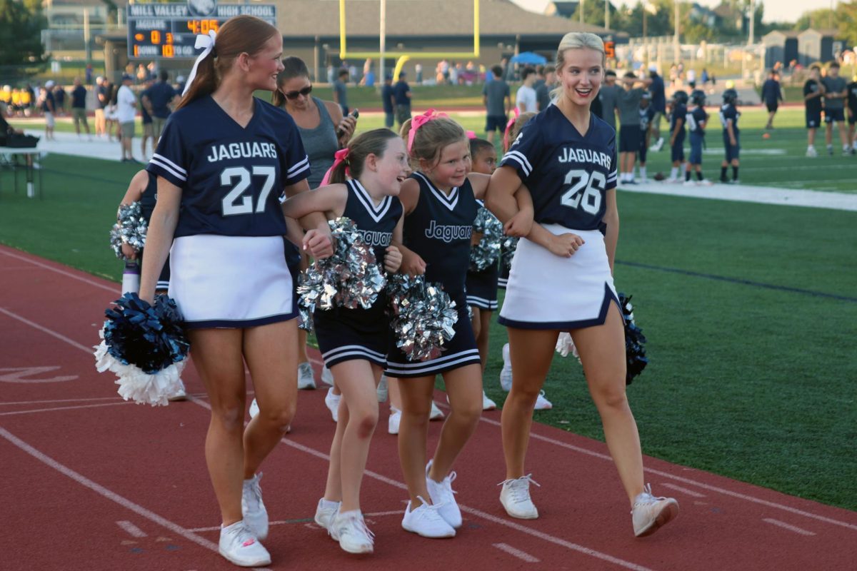 Arms linked, Junior Annie Bohon and Senior Brynlee Sword walk with their Junior Jag cheerleaders.