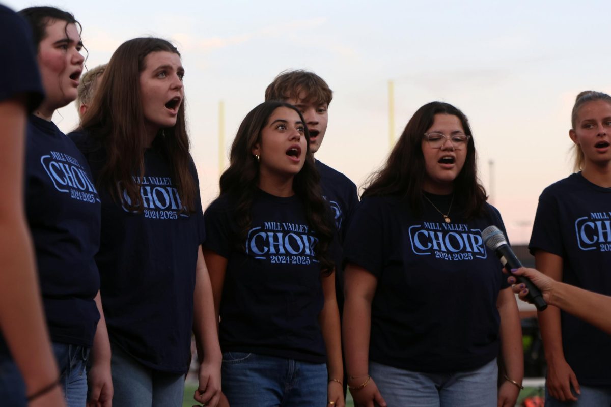 Seniors Samantha McCoy and Josey Crossley and juniors Amalia Oropeza and Lucy Suman sing the National Anthem with the choir before the high school scrimmage begins.