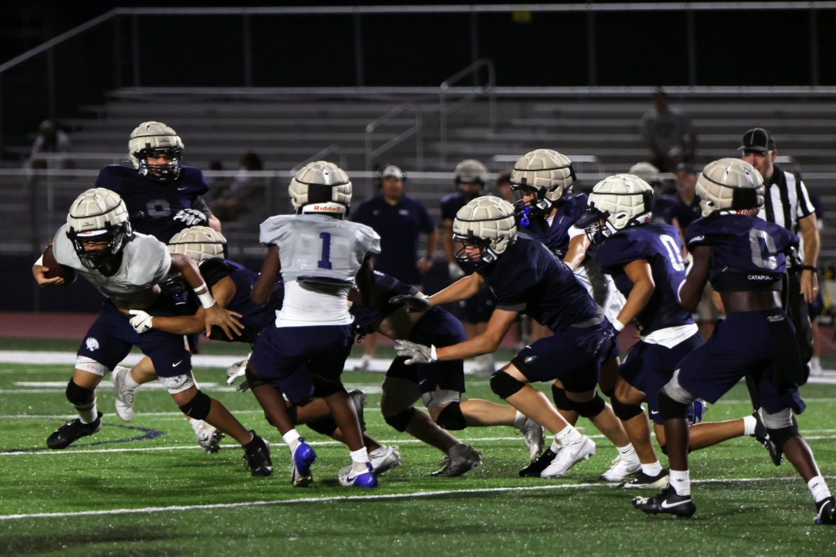 Held back, football team member attempts to make a break away with the ball.