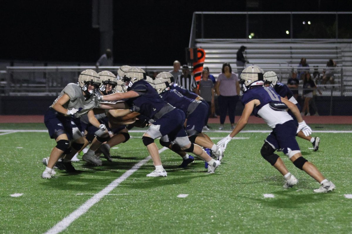 Trying to push each other back, the blue team plays defence against the silver team to keep their quarterback from getting tackled, Thursday, Aug. 28. 