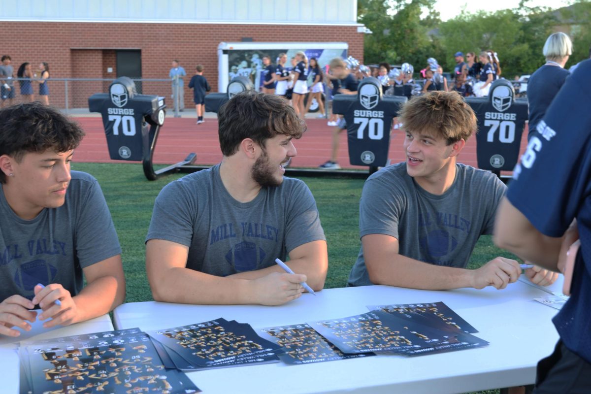 Seniors ____, Cameron Plaud, and Devon Edwards sign autographs for junior football players and other fans.