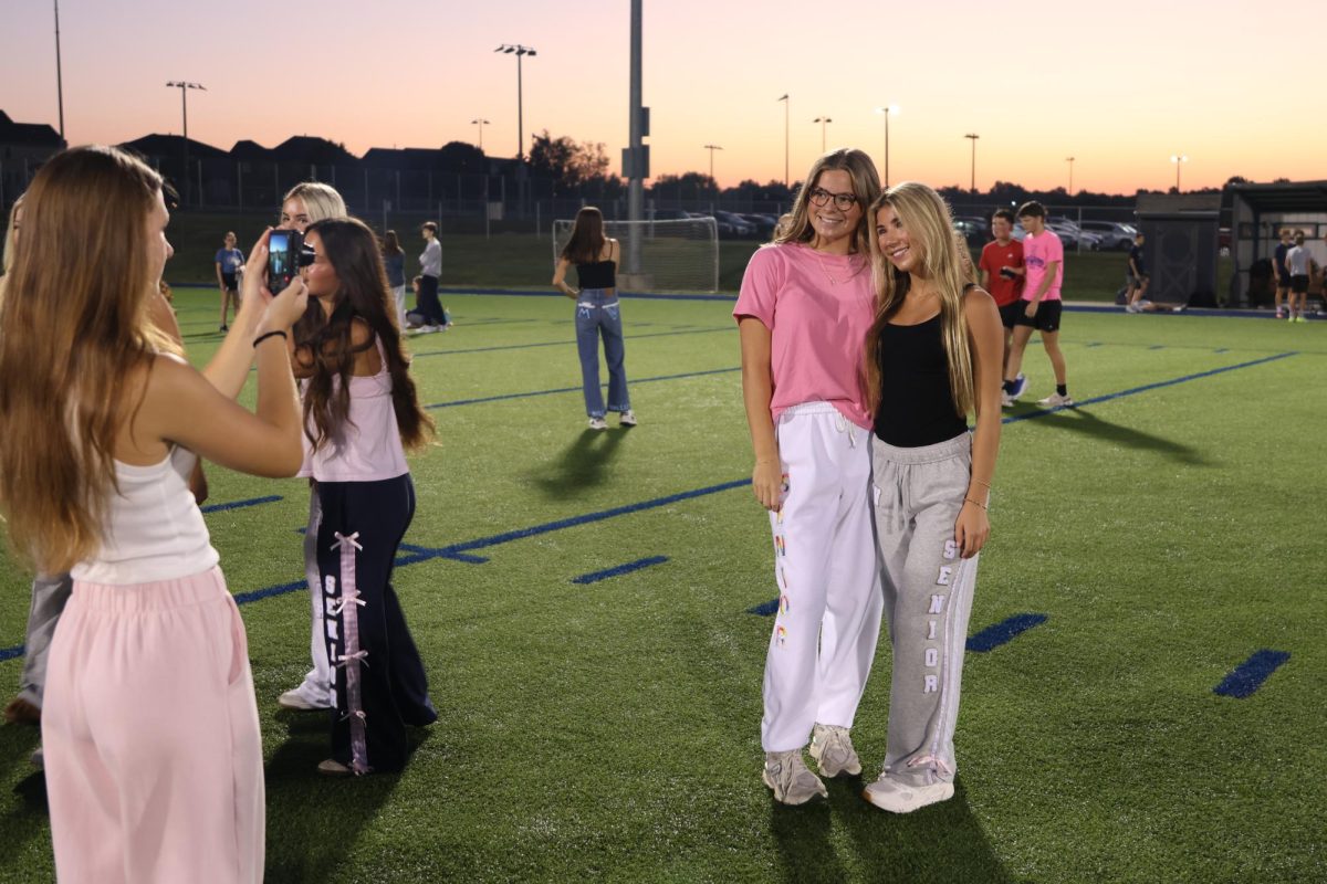 Wearing their senior sweatpants, senior Lola Dumler and Sydney Epperson pose for a photo. 