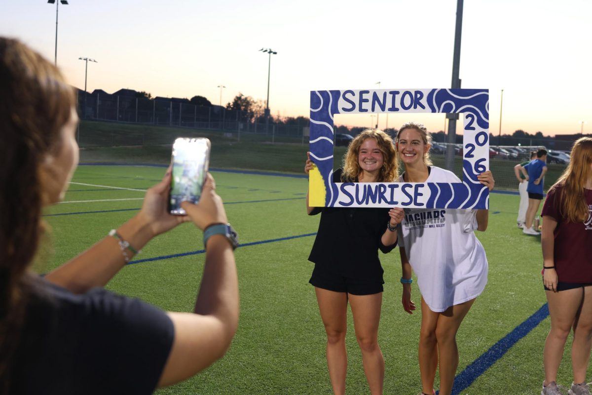 Holding up their homemade sign, seniors Kylie Stegner and Mae Reynolds get a picture to capture the memory of senior sunrise, Aug, 20.