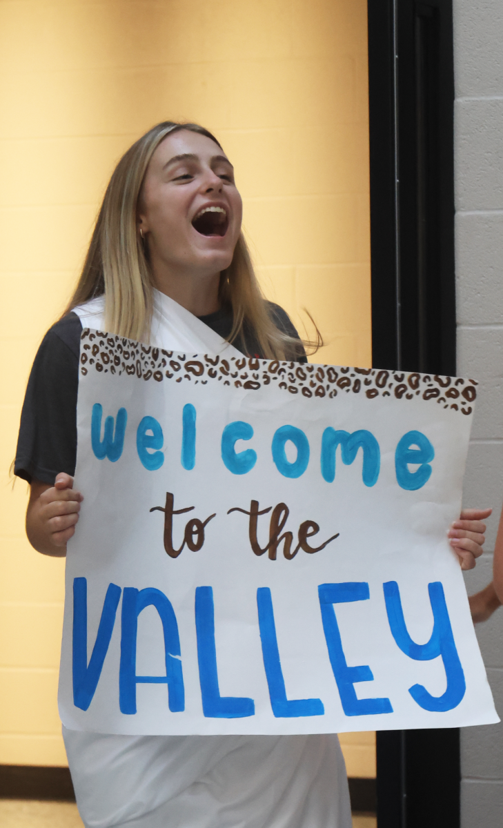 Holding her sign, junior Riley Marshall welcomes the new freshmen into the gym.