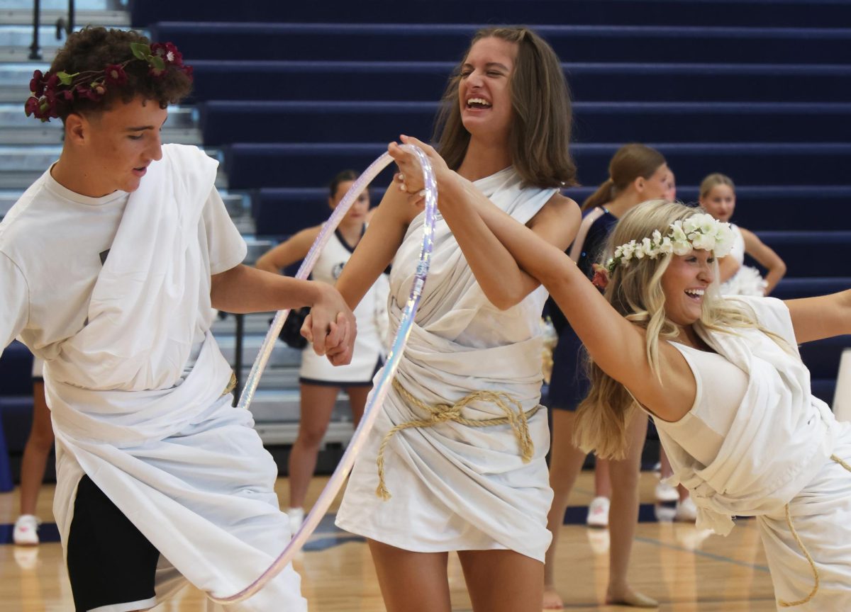 Laughing, senior Mae Reynolds, junior Reese Miller and sophomore Kaleb Davis participate in a fun challenge during the pep assembly.