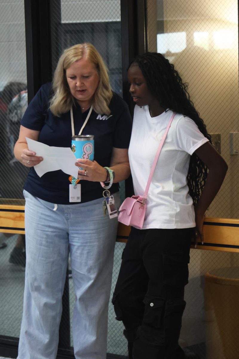 Looking at her schedule, counselor Mrs Chandler helps a freshman find her class.
