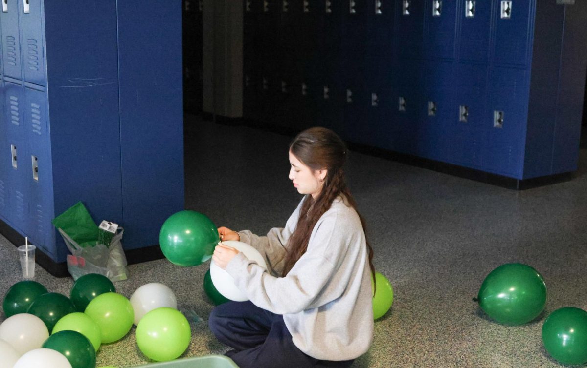 Sophomore Elynne Strack ties a bunch of balloons together 