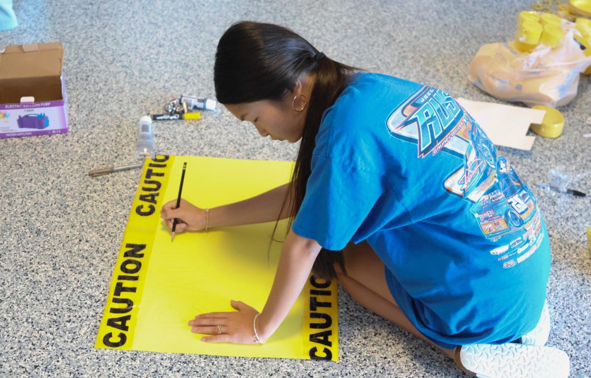 Freshman Kate Nguyen writes on the freshman sign 